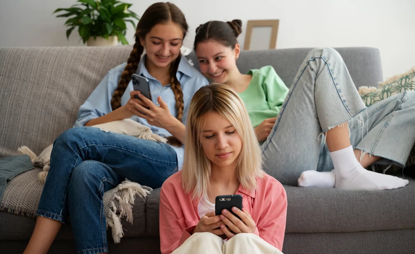 Adolescentes em um sofá usando smartphones.